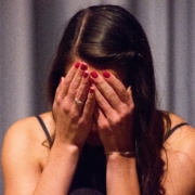 woman with her hands on her head crying with curtains in the background