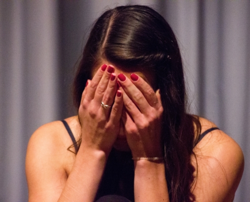 woman with her hands on her head crying with curtains in the background